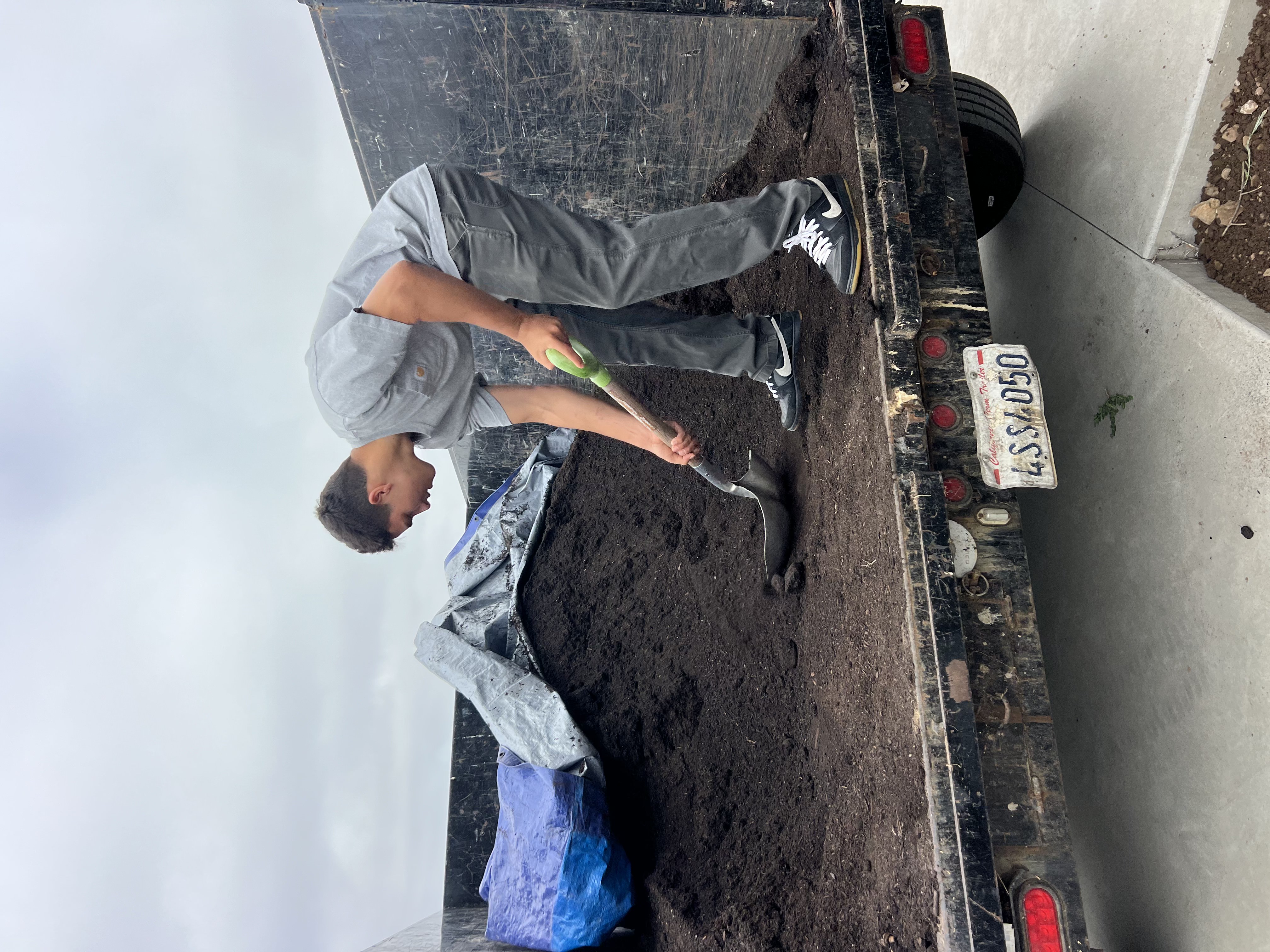 Shoveling soil out of the dump trailer by hand